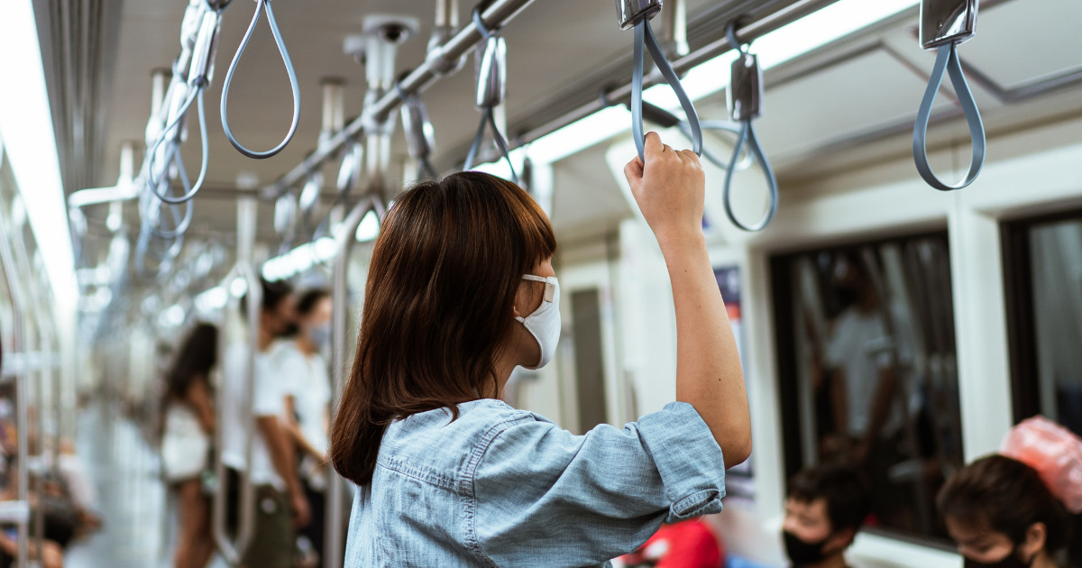 電車で吊革につかまる女性の写真